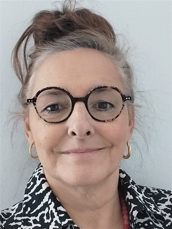 Marie-Laure, souriante, lunettes rondes et chignon